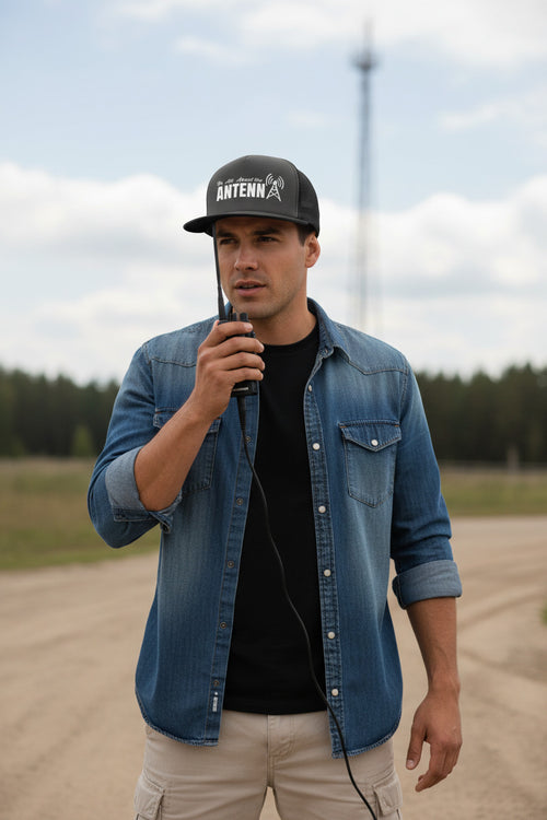 Black trucker hat with white text and antenna graphic on a white background